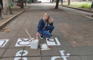 Библиотекарка изрисува вход пред читалище със символи от глаголицата